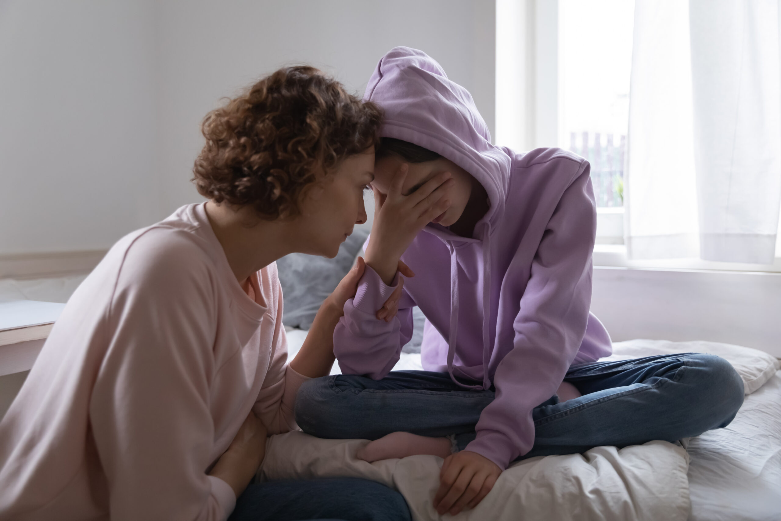 Worried mom comforting depressed teen daughter crying at home Worried mom comforting depressed teen daughter crying at home